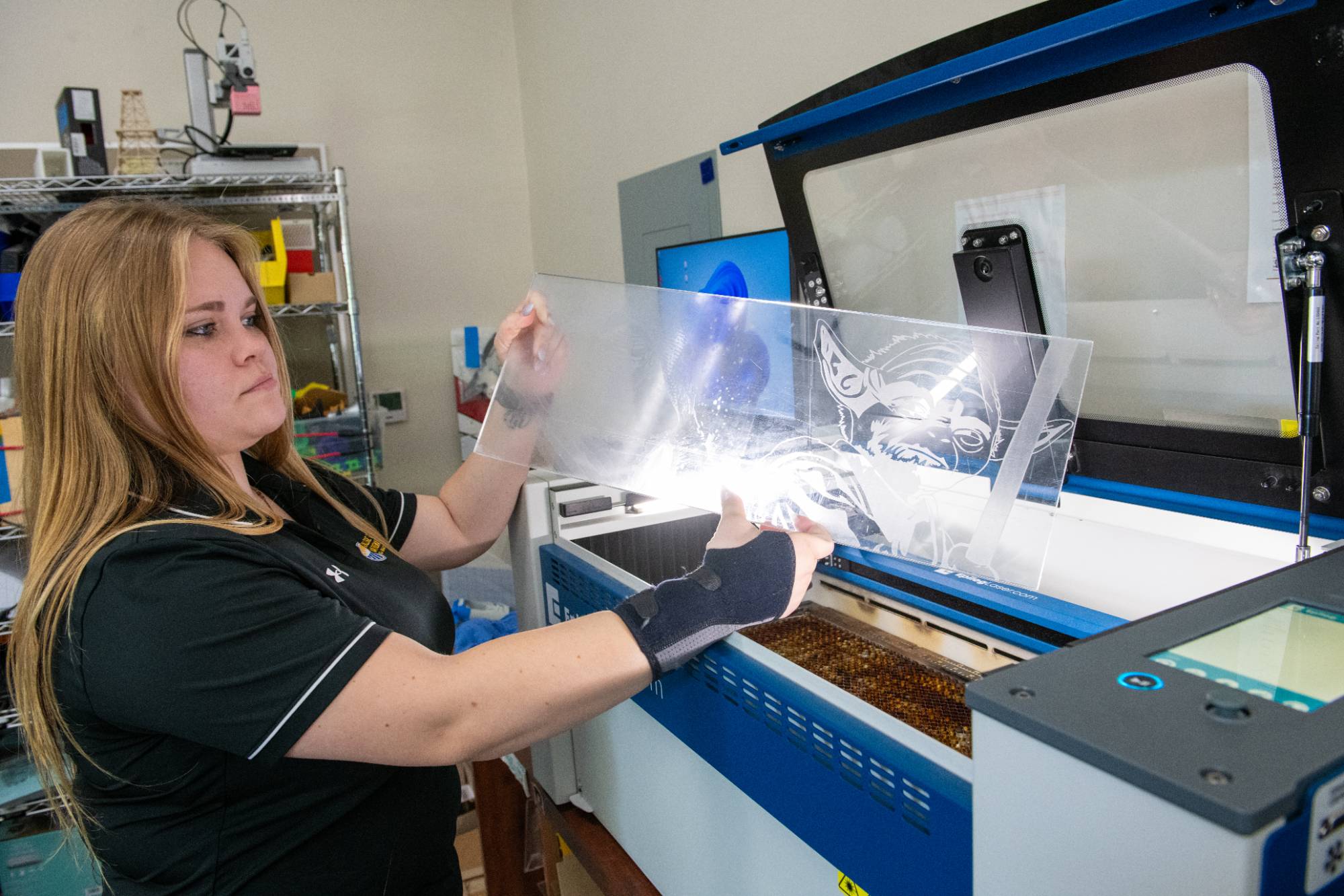 Fab Lab intern working at laser cutter machine.